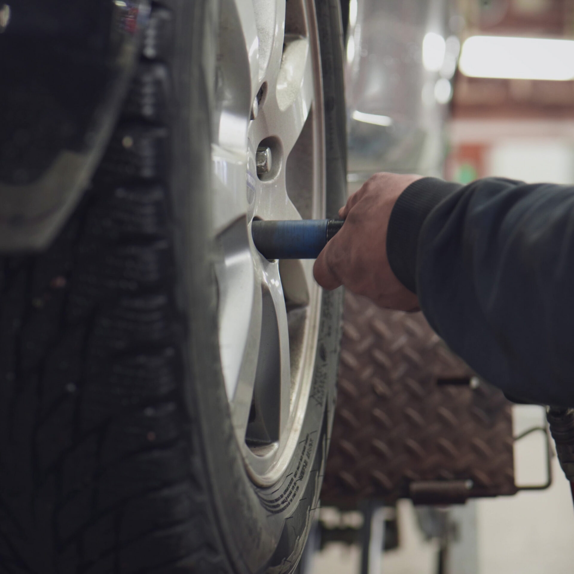 Helmia tekniker hand använder luftdriven mutterdragare på bilhjul i garage