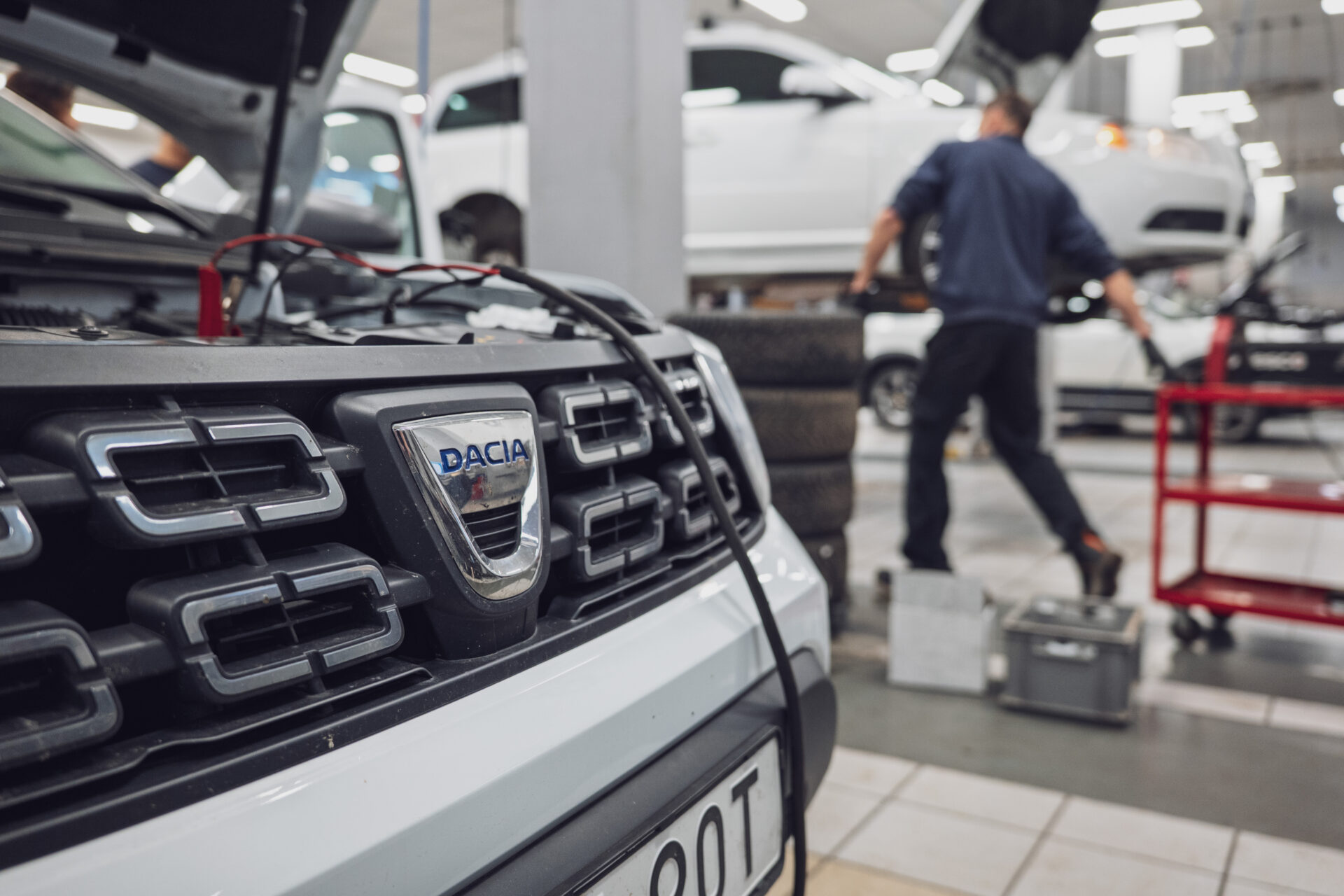 Närbild på Dacia-emblem på bilens front inne i en Helmia-verkstad i Karlstad med en mekaniker i bakgrunden