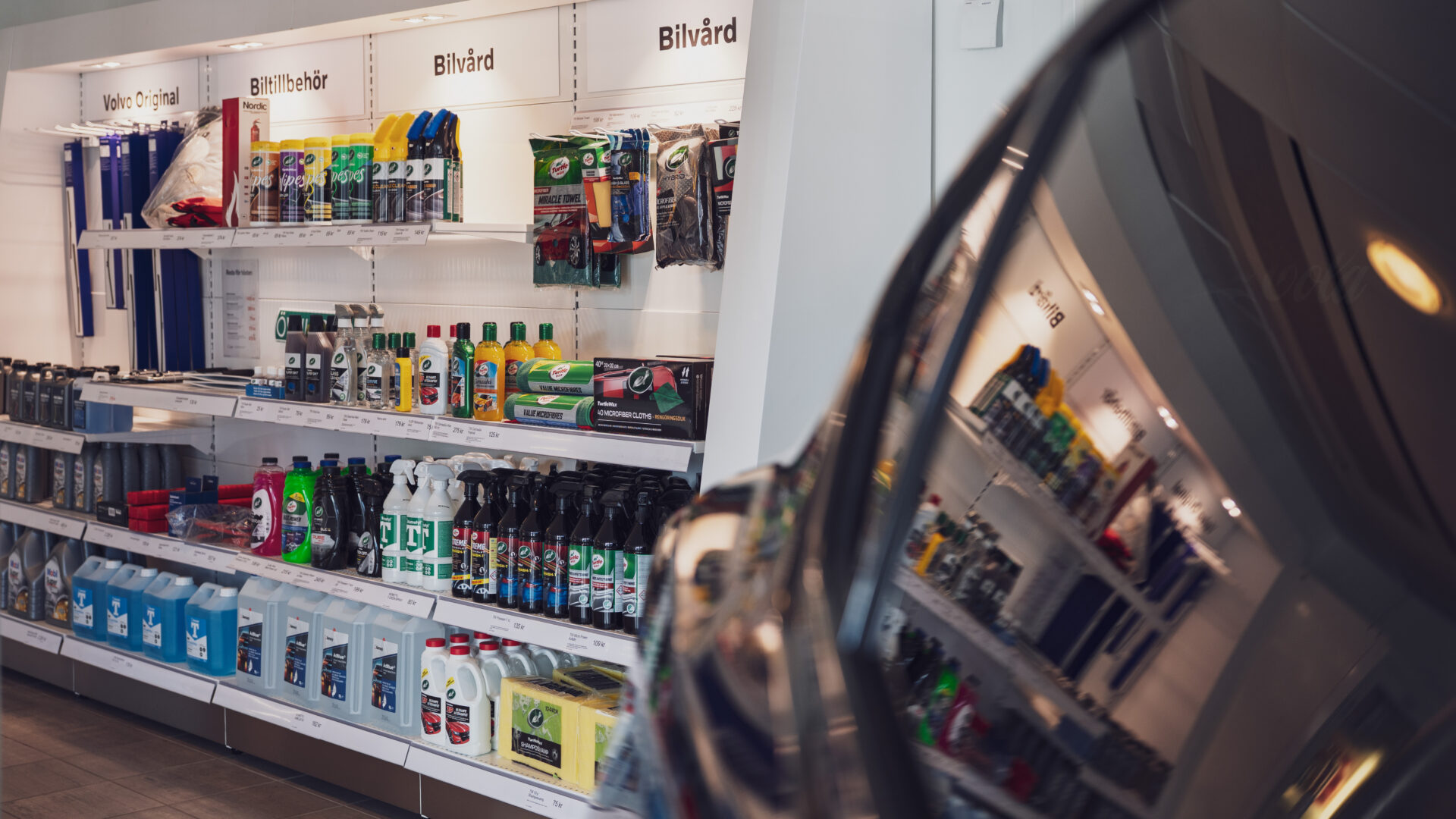 Helmia butik i Karlstad med bilvårdsprodukter och Volvo Original på hyllor speglade i en blank bil