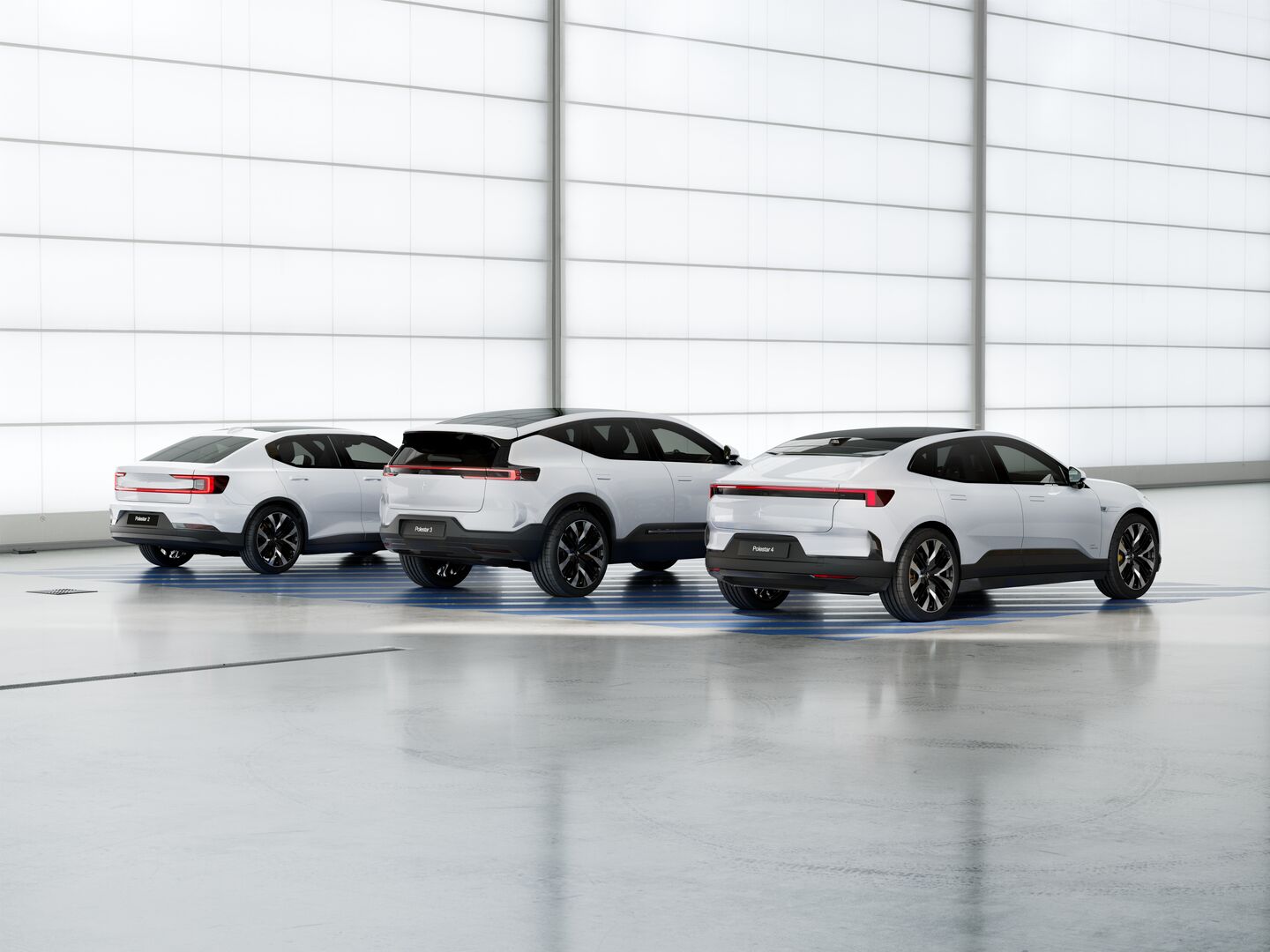 Bak-trea vy av tre vita Polestar elbilar parkerade i ett ljust, modernt showroom med reflekterande golv hos Helmia