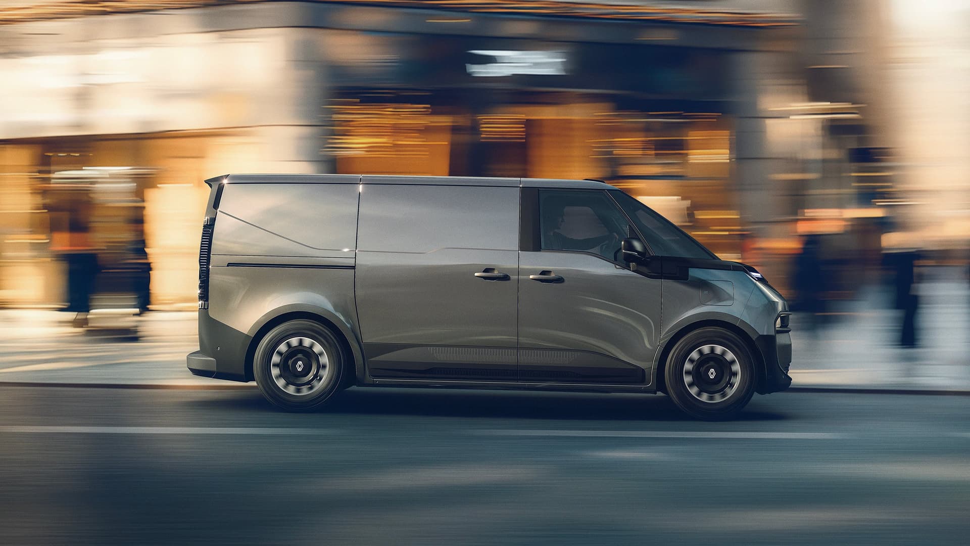 Sidovy av futuristisk grå Renault Trafic E-Tech electric skåpbil som kör med suddig stadsmiljö i bakgrunden i Helmia